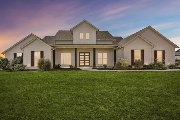 a front view of a house with a yard and trees