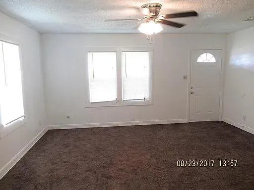 an empty room with windows and fan