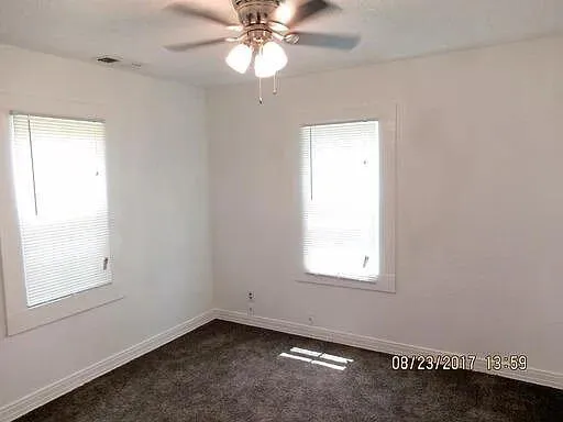 an empty room with a window and a chandelier fan