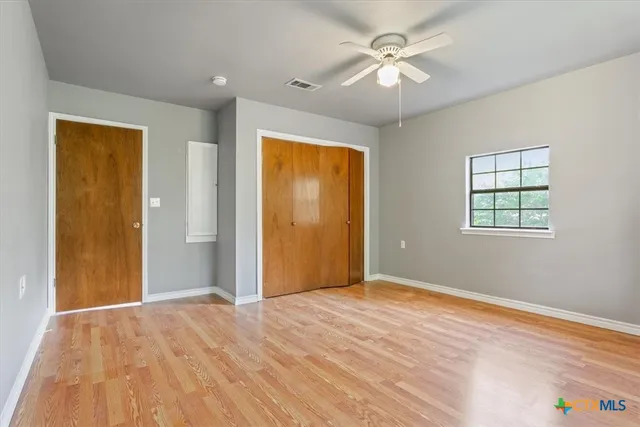 a view of an empty room with window and a ceiling fan