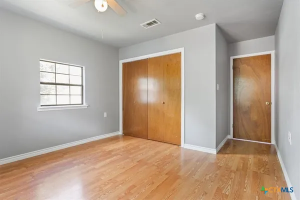 a view of an empty room with wooden floor and a window