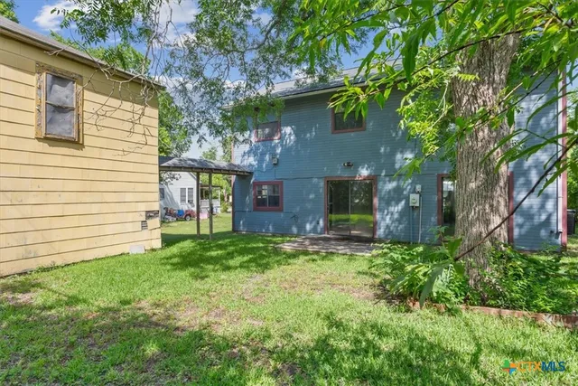a view of a house with a yard and a large tree