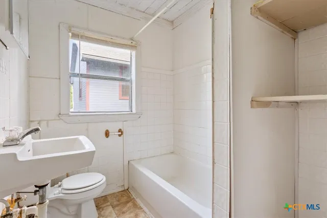 a white toilet sitting next to a bath tub