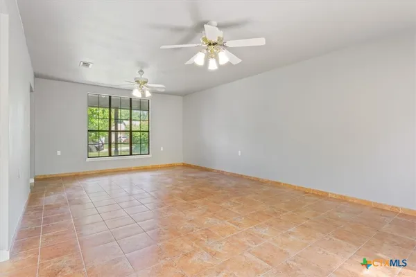 an empty room with windows and chandelier fan