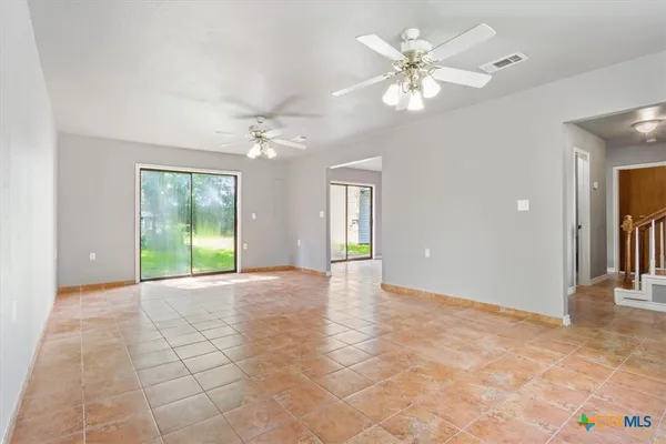a view of an empty room with a chandelier fan