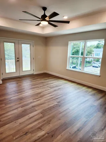 a view of an empty room with wooden floor and a window