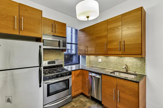 a kitchen with stainless steel appliances granite countertop a sink and a refrigerator