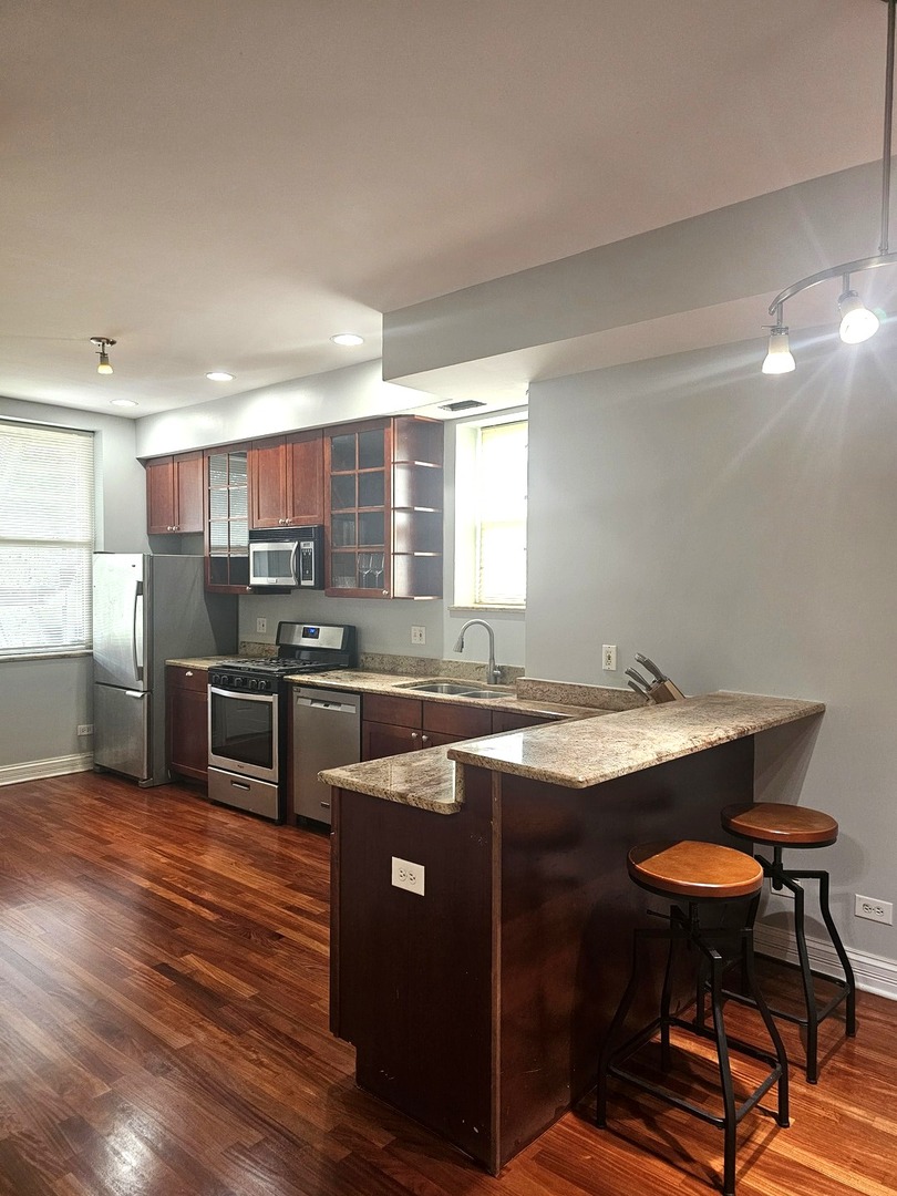 1520 East Marquette Road, Unit 2B Chicago, IL 60637 - Photo 24 of 44 a kitchen with stainless steel appliances granite countertop a sink a stove a refrigerator counter and chairs
