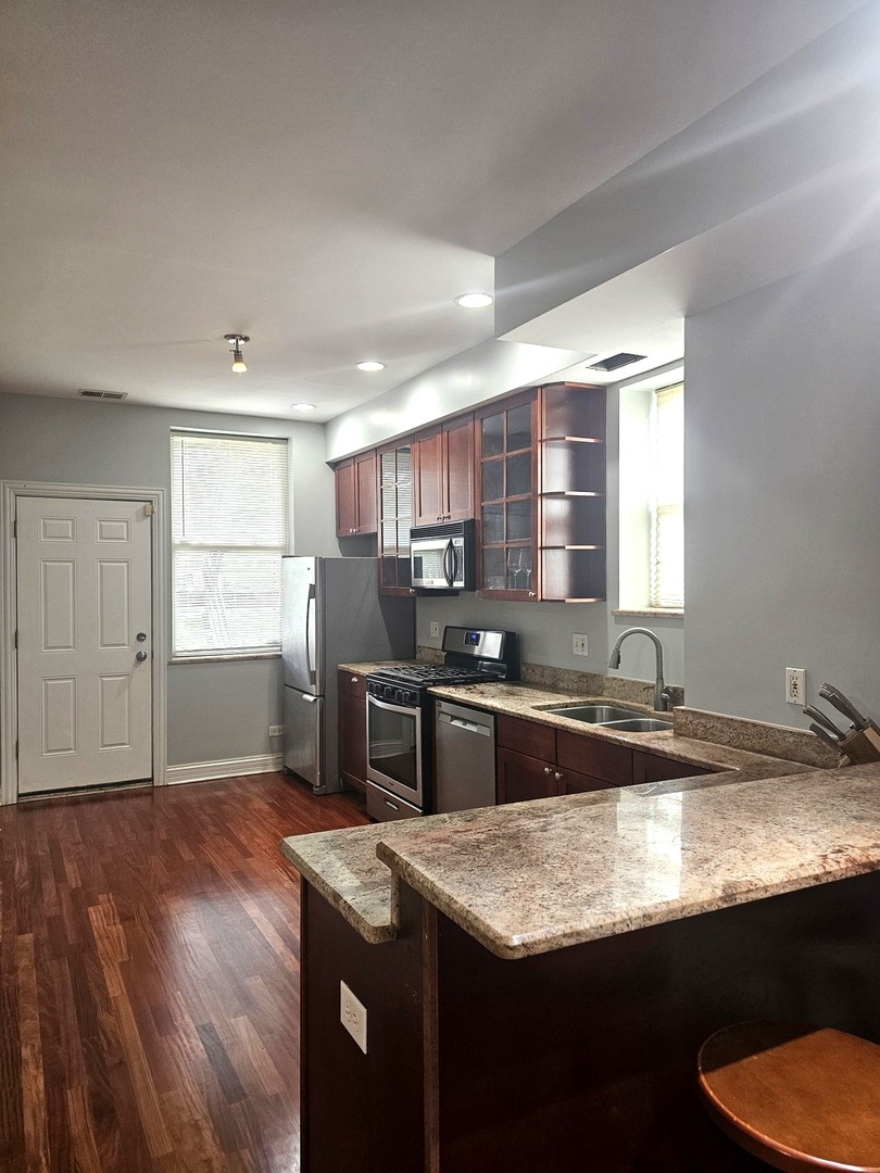 1520 East Marquette Road, Unit 2B Chicago, IL 60637 - Photo 25 of 44 a kitchen with kitchen island granite countertop a sink cabinets and wooden floor
