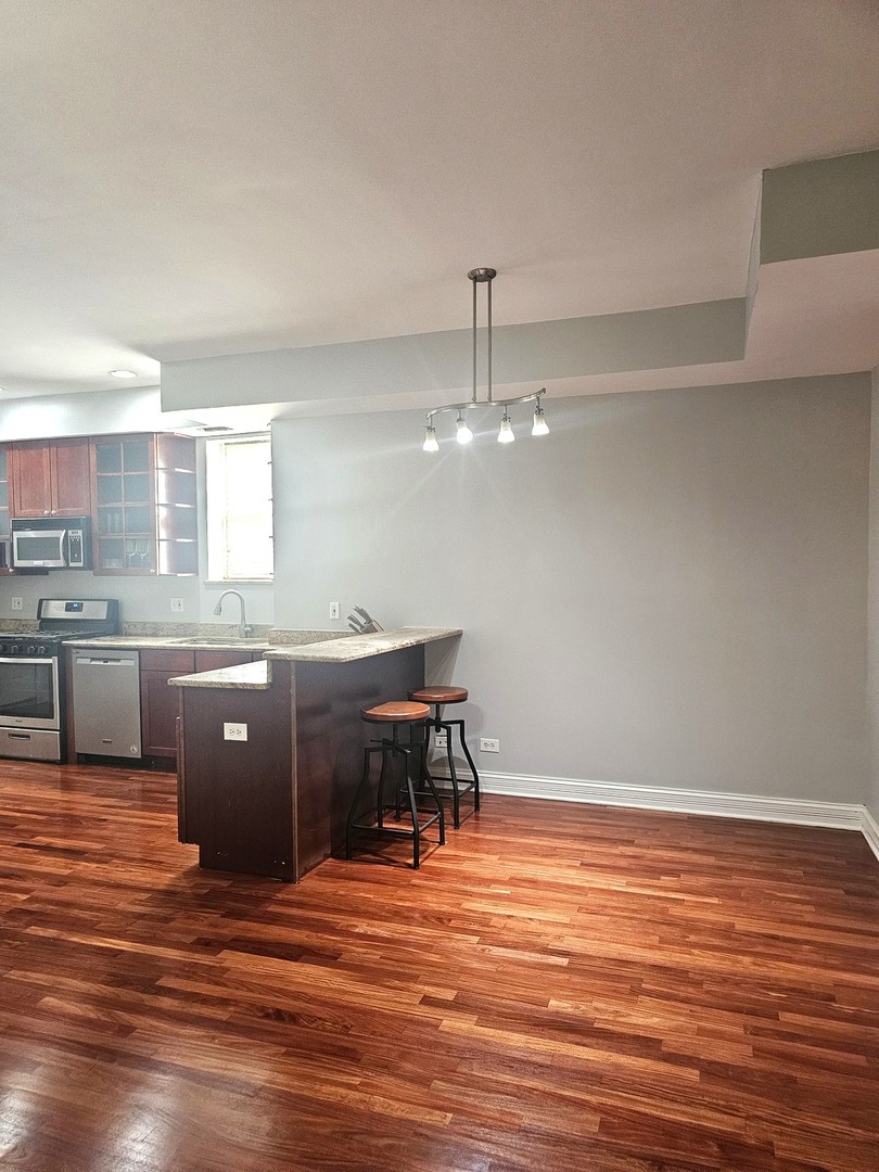 1520 East Marquette Road, Unit 2B Chicago, IL 60637 - Photo 26 of 44 a kitchen with stainless steel appliances granite countertop a sink counter space and wooden floor