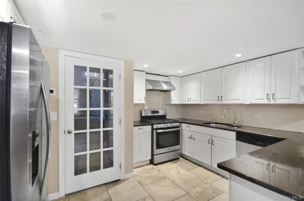 a large kitchen with stainless steel appliances kitchen island granite countertop a refrigerator and a stove top oven