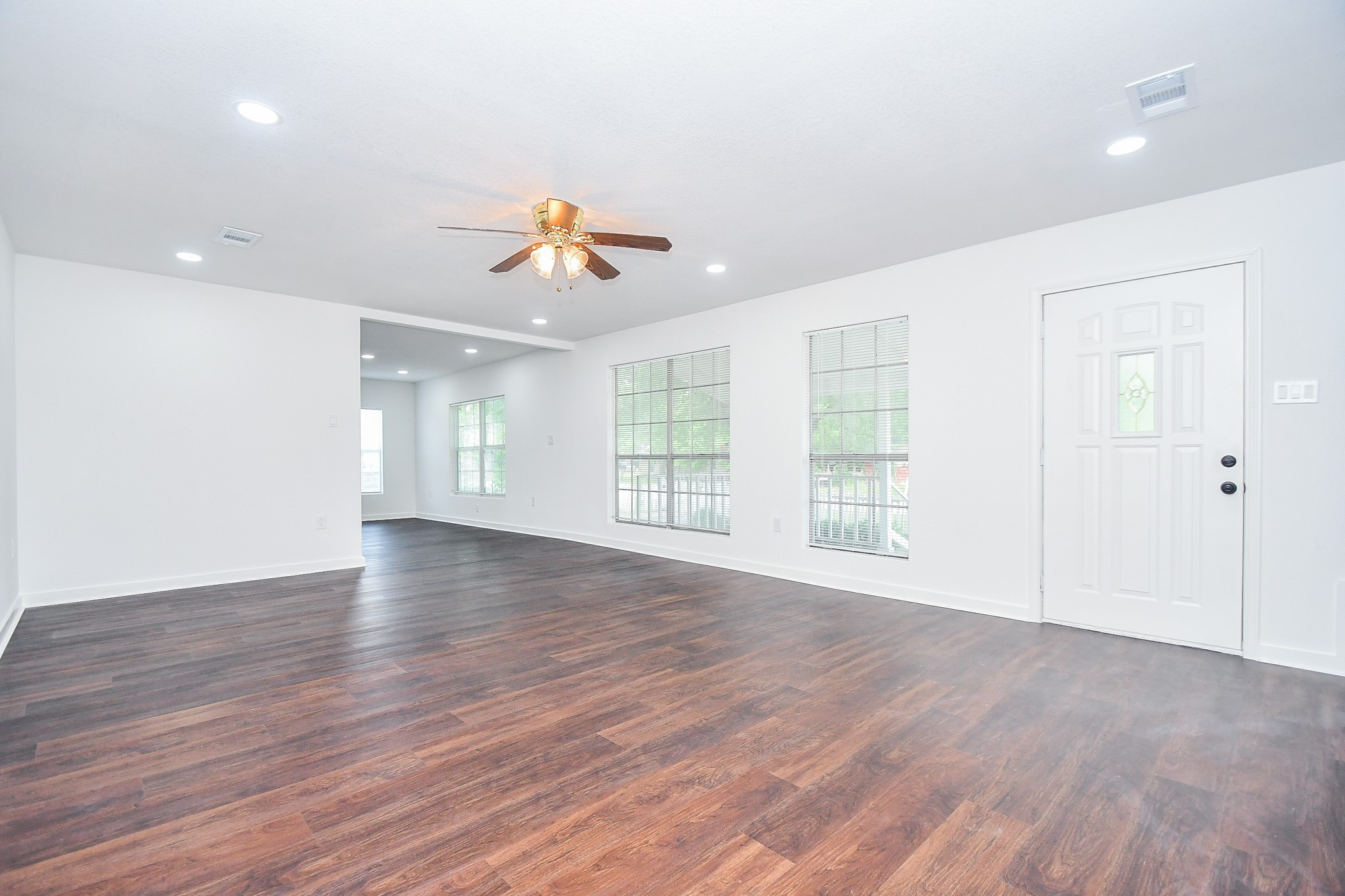 2636 Lone Oak Road Houston, TX 77093 - Photo 12 of 42 This spacious living area features rich wood flooring, large windows for natural light, and a ceiling fan for comfort. The open layout offers a seamless flow to the next room, and the front door adds a welcoming touch.