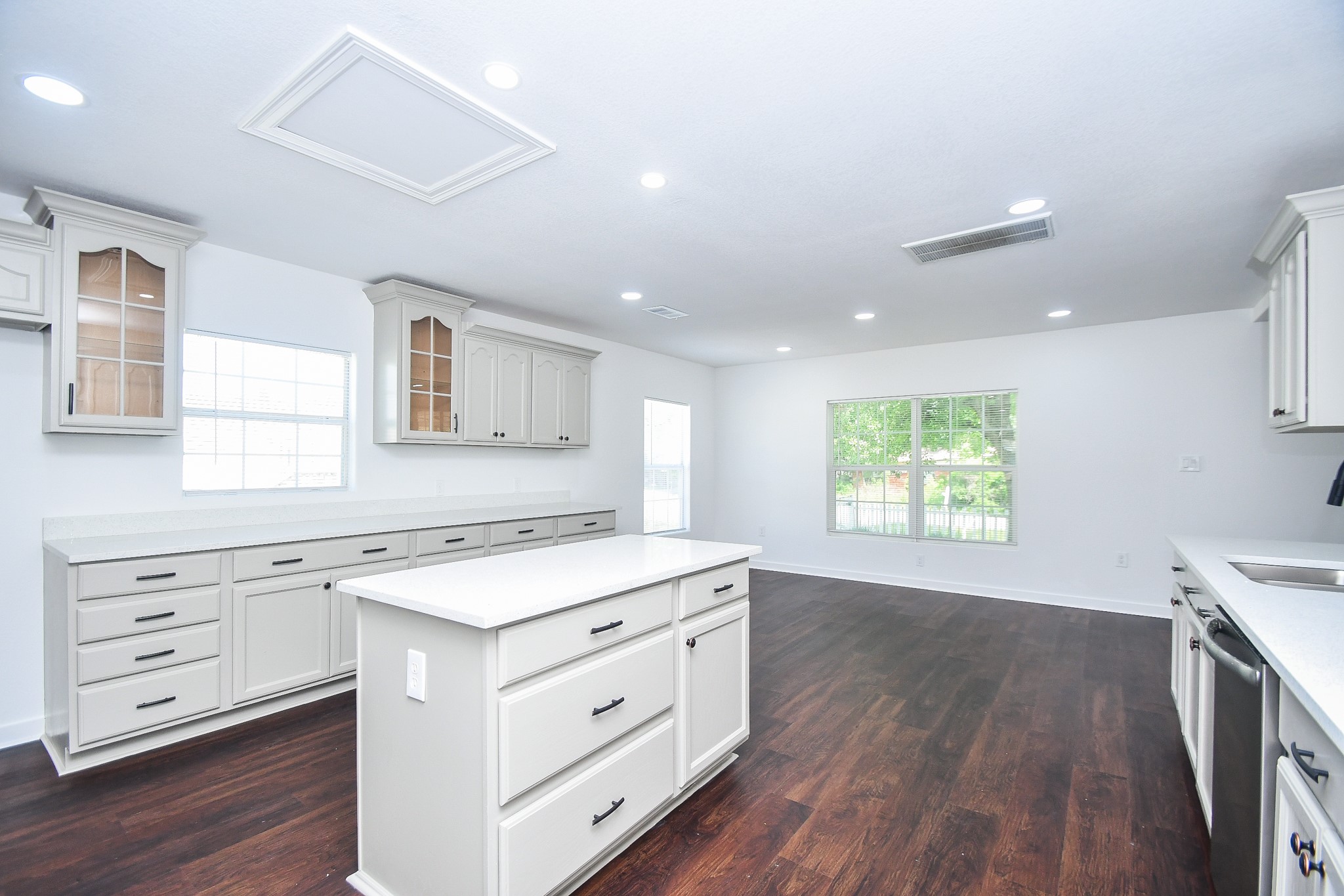 2636 Lone Oak Road Houston, TX 77093 - Photo 16 of 42 Spacious, modern kitchen with white cabinetry, a large island, and dark hardwood floors. The room is well-lit with recessed lighting and large windows, offering a bright and airy feel.