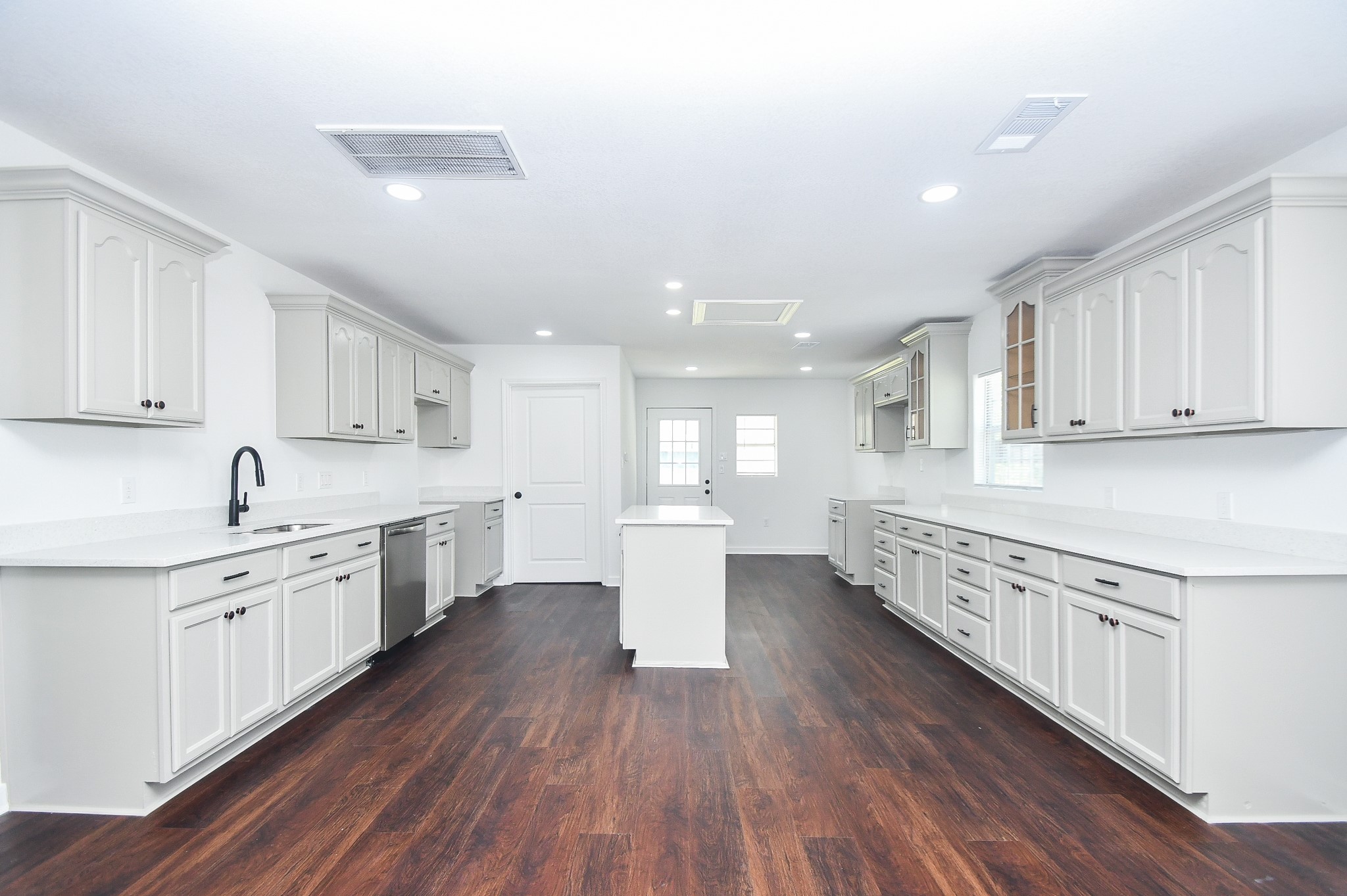 2636 Lone Oak Road Houston, TX 77093 - Photo 6 of 42 This kitchen features a bright, open layout with ample cabinetry, modern fixtures, and sleek countertops. The dark wood flooring contrasts elegantly with light-colored cabinets, providing a spacious and inviting atmosphere. Ideal for entertaining and culinary activities.
