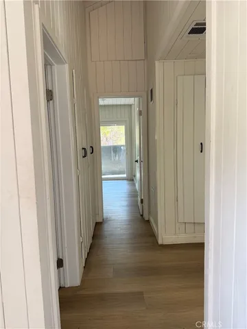 an empty room with wooden floor closet and windows