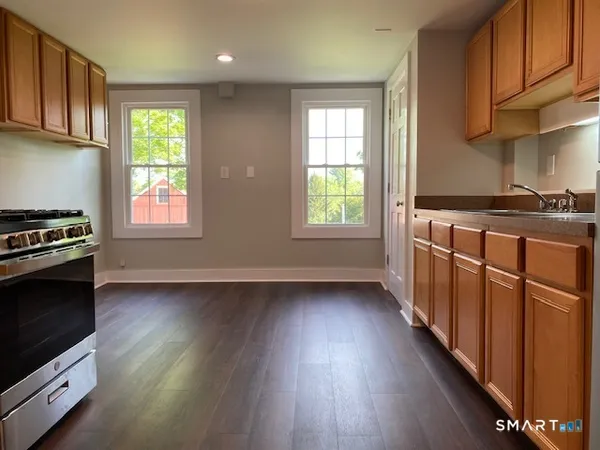 a kitchen with stainless steel appliances a stove a sink wooden floor and a window