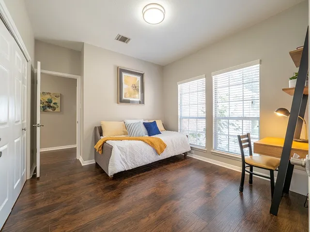 a spacious bedroom with a bed and wooden floor
