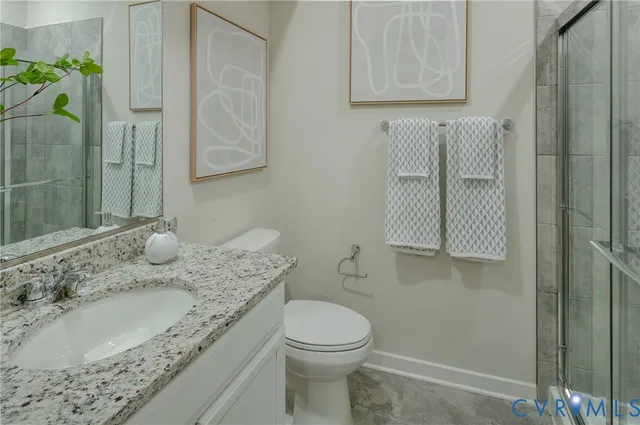 a bathroom with a granite countertop sink a toilet and a shower
