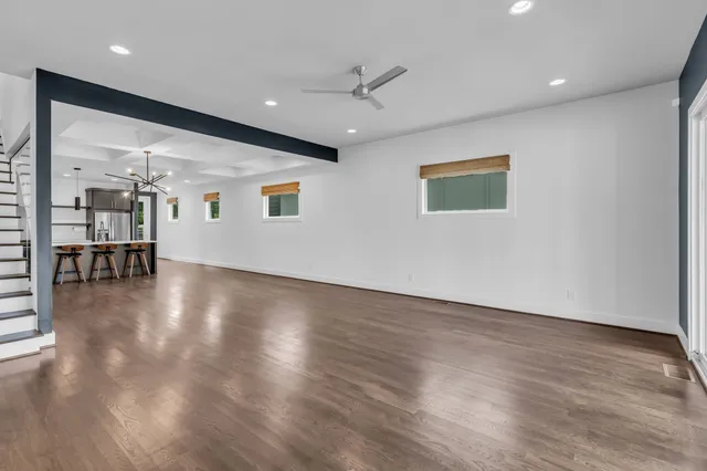 an empty room with wooden floor and a ceiling fan