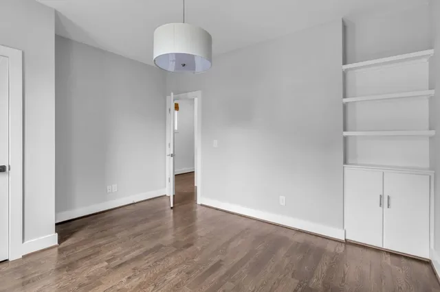 an empty room with wooden floor and cabinet