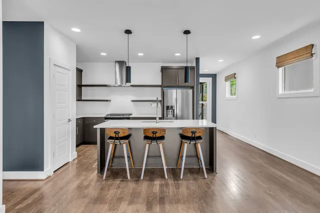 a kitchen with stainless steel appliances granite countertop a dining table chairs refrigerator and microwave