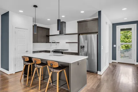 a kitchen with stainless steel appliances granite countertop a refrigerator a sink dishwasher a stove and a refrigerator with wooden floor