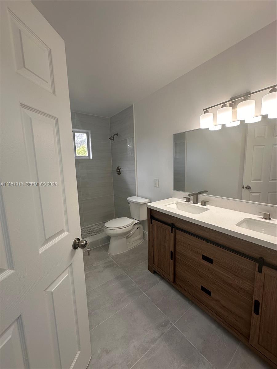 8950 Northwest 189th Terrace Hialeah, FL 33018 - Photo 20 of 42 a bathroom with a double vanity sink toilet mirror and bathtub