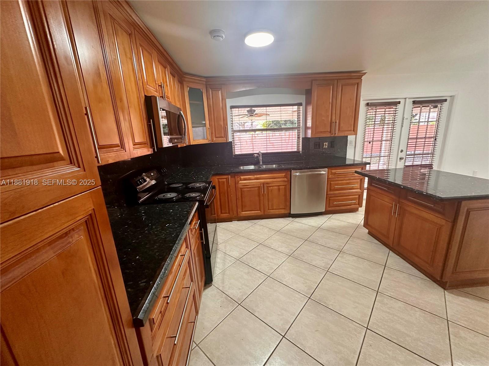 8950 Northwest 189th Terrace Hialeah, FL 33018 - Photo 5 of 42 a kitchen with granite countertop a refrigerator a stove top oven and sink