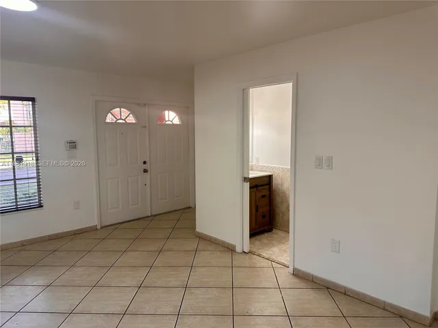 a view of an empty room with window and chandelier fan