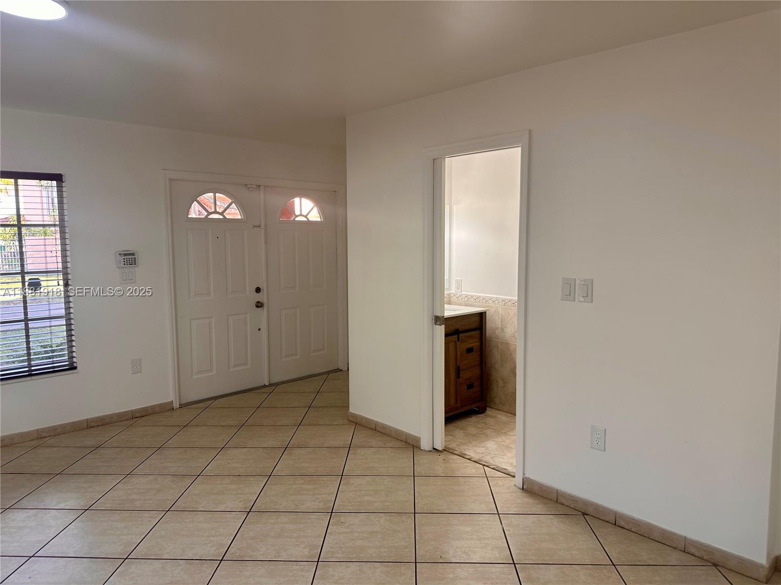 8950 Northwest 189th Terrace Hialeah, FL 33018 - Photo 8 of 42 a view of an empty room with window and chandelier fan