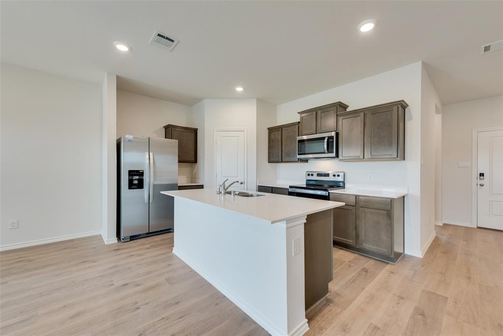 1428 Millstead Rill Drive Caddo Mills, TX 75135 - Photo 4 of 24 a kitchen with kitchen island a sink stainless steel appliances and cabinets