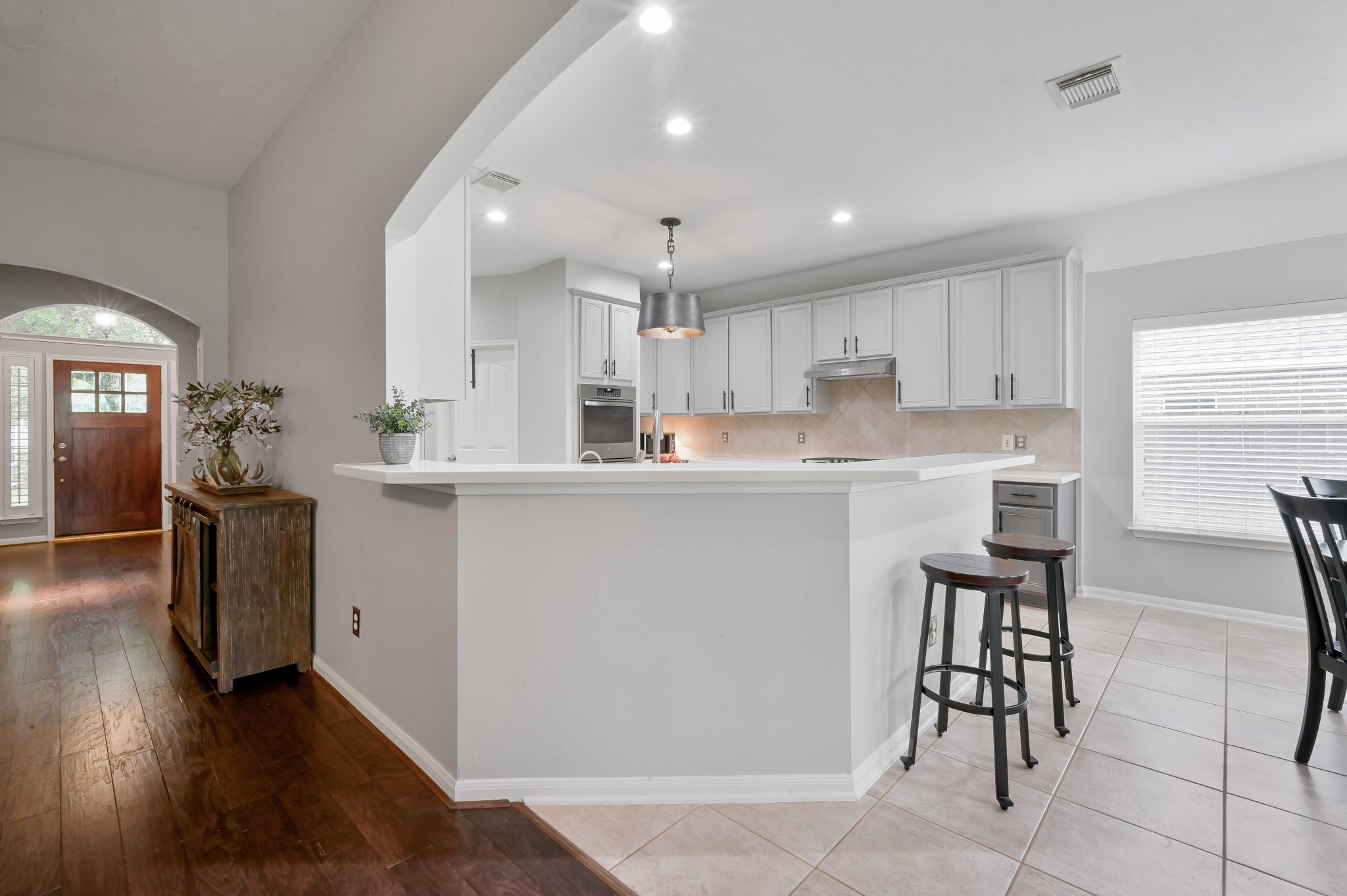 2 Westward Ridge Place The Woodlands, TX 77384 - Photo 14 of 43 Open kitchen with two-tone gray painted maple wood cabinets, breakfast bar, and modern lighting