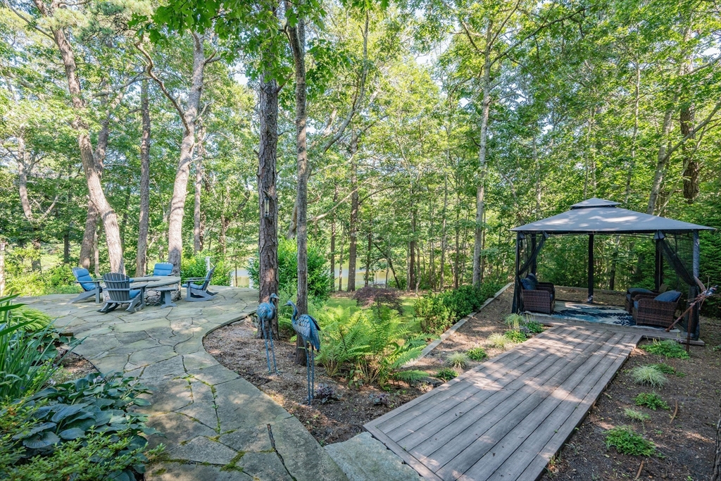 290 Old Comers Road Chatham, MA 02633 - Photo 28 of 40 a view of a backyard with chairs under an umbrella