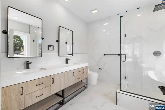 a spacious bathroom with double vanity a double vanity sink a shower and a mirror