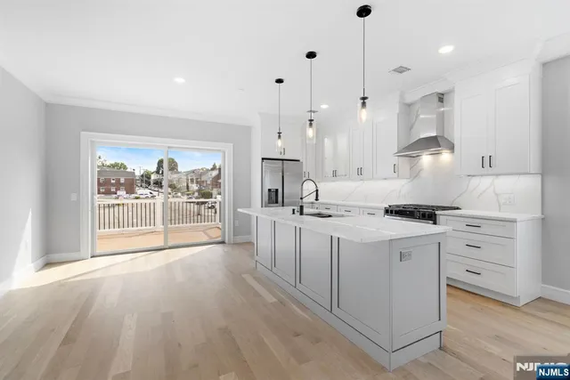 a large kitchen with kitchen island white cabinets and stainless steel appliances