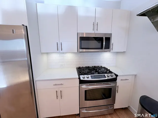 a kitchen with granite countertop white cabinets and white stove