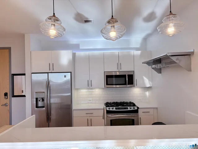 a kitchen with stainless steel appliances granite countertop a refrigerator a stove and a microwave