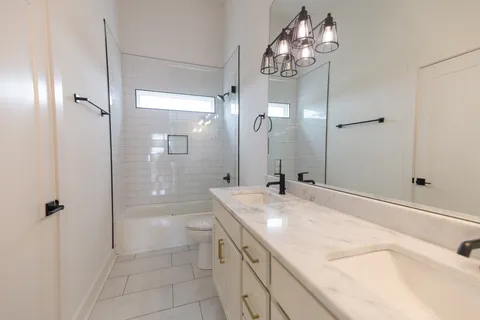 a bathroom with a granite countertop sink a toilet and shower
