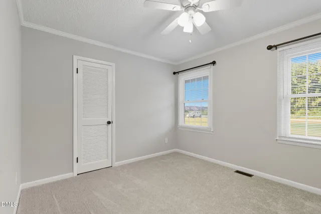 an empty room with windows and fan