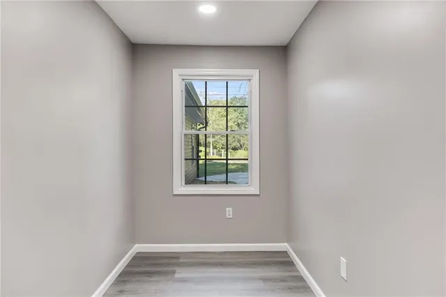 a view of an empty room with wooden floor and a window