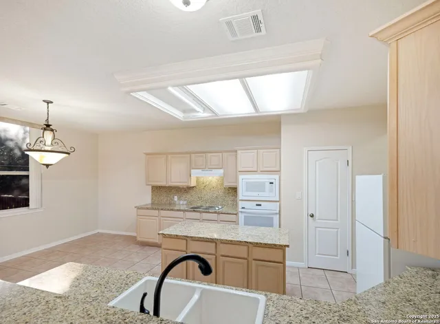 a kitchen with kitchen island granite countertop a stove a sink and a refrigerator
