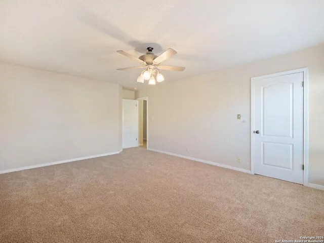 an empty room with a chandelier fan and closet