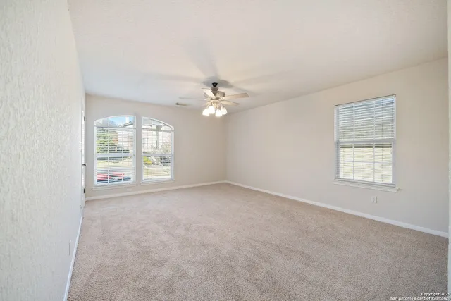 an empty room with windows and chandelier fan