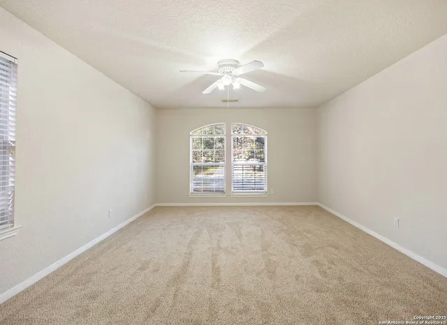 an empty room with a window and a fan