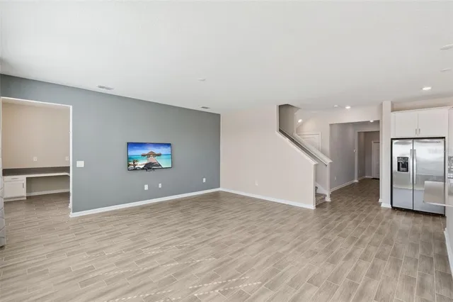 a view of a livingroom with wooden floor and a kitchen