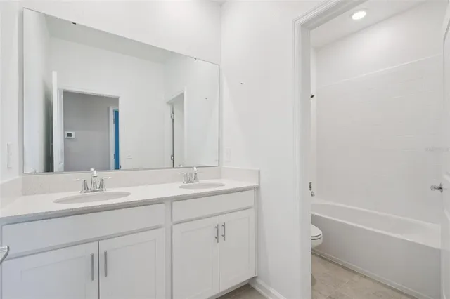 a bathroom with a double vanity sink a mirror and a bathtub