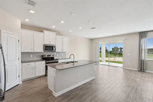 a kitchen with stainless steel appliances granite countertop a stove a sink and a refrigerator