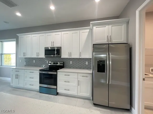 an empty room with kitchen view and windows