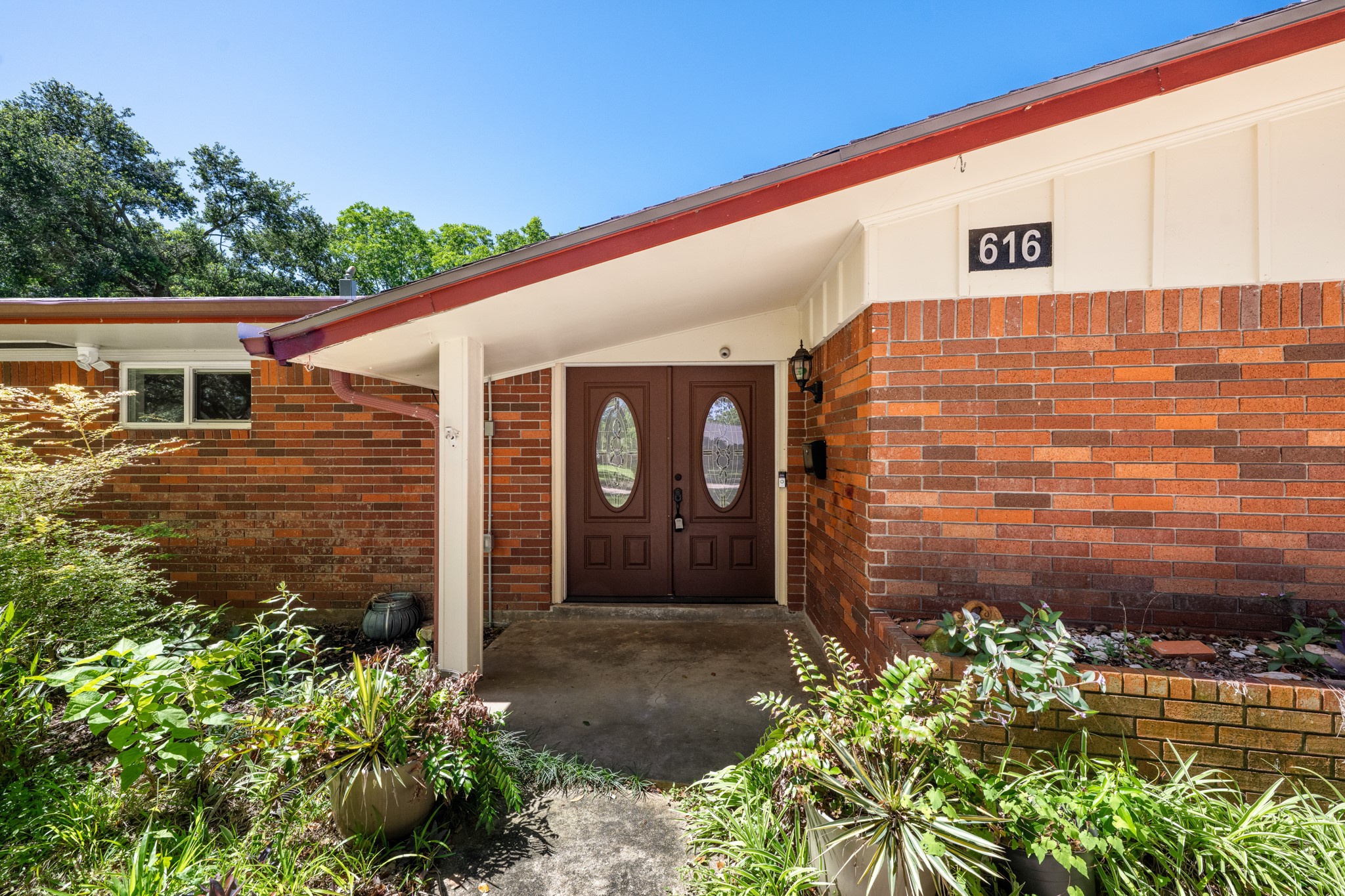 616 Cannan Drive Angleton, TX 77515 - Photo 2 of 49 A covered front porch welcomes guests with distinctive double entry doors and classic brick architecture. Thoughtfully landscaped planting beds and the sheltered entry create an inviting first impression while offering protection from the elements.