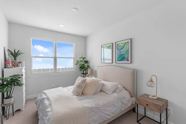 a bedroom with a bed table chair and a window